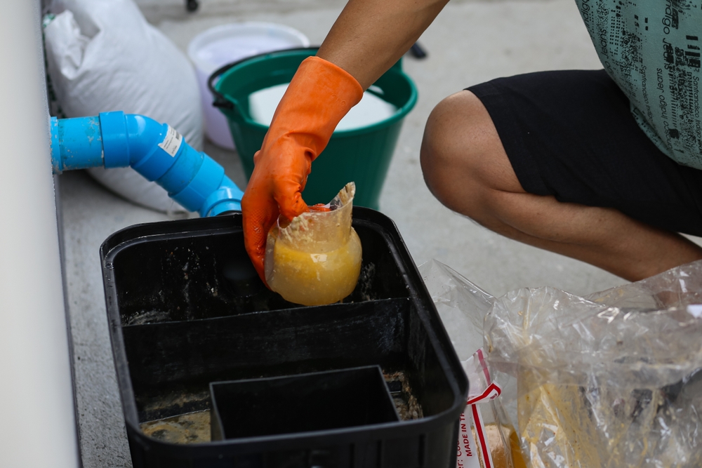 A,Man,Cleaning,A,Grease,Traps,Box,Outside,The,House,